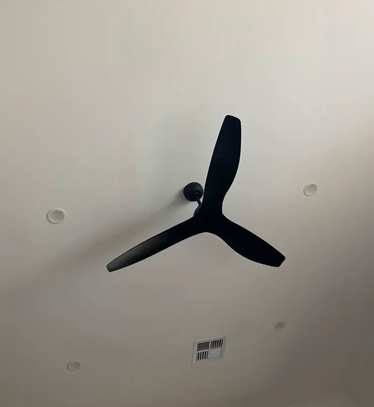 Black three-blade ceiling fan on a ceiling with LED downlights and ducted outlets