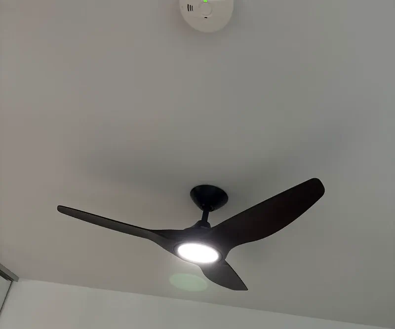 Black three-blade ceiling fan with its LED light switched on