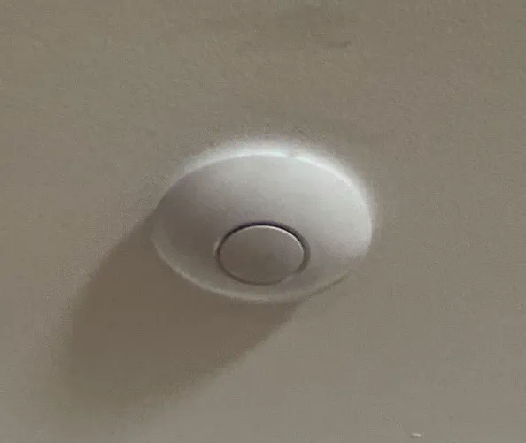 Round white ceiling-mounted smoke alarm with a centre test button