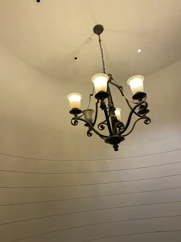 Five-arm chandelier with glass shades hanging from a high curved ceiling