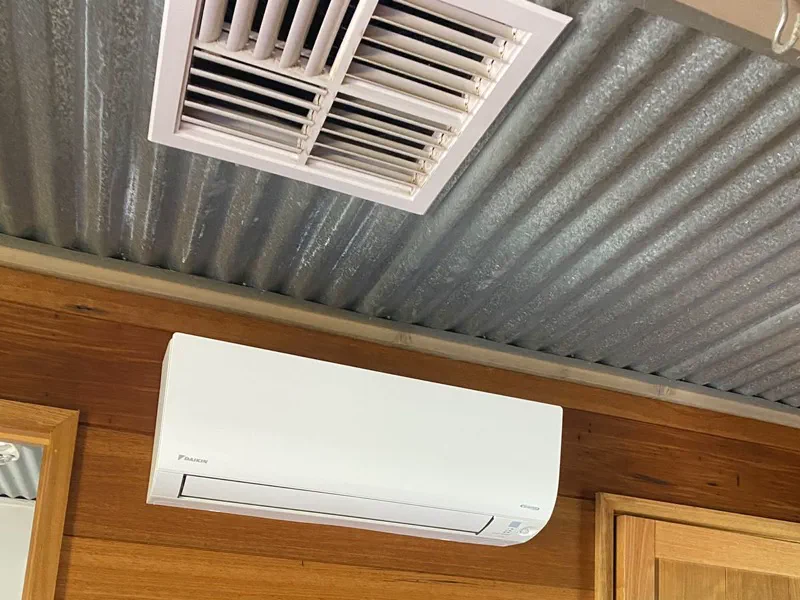 Daikin wall-mounted split system on a timber-lined wall under a corrugated iron ceiling