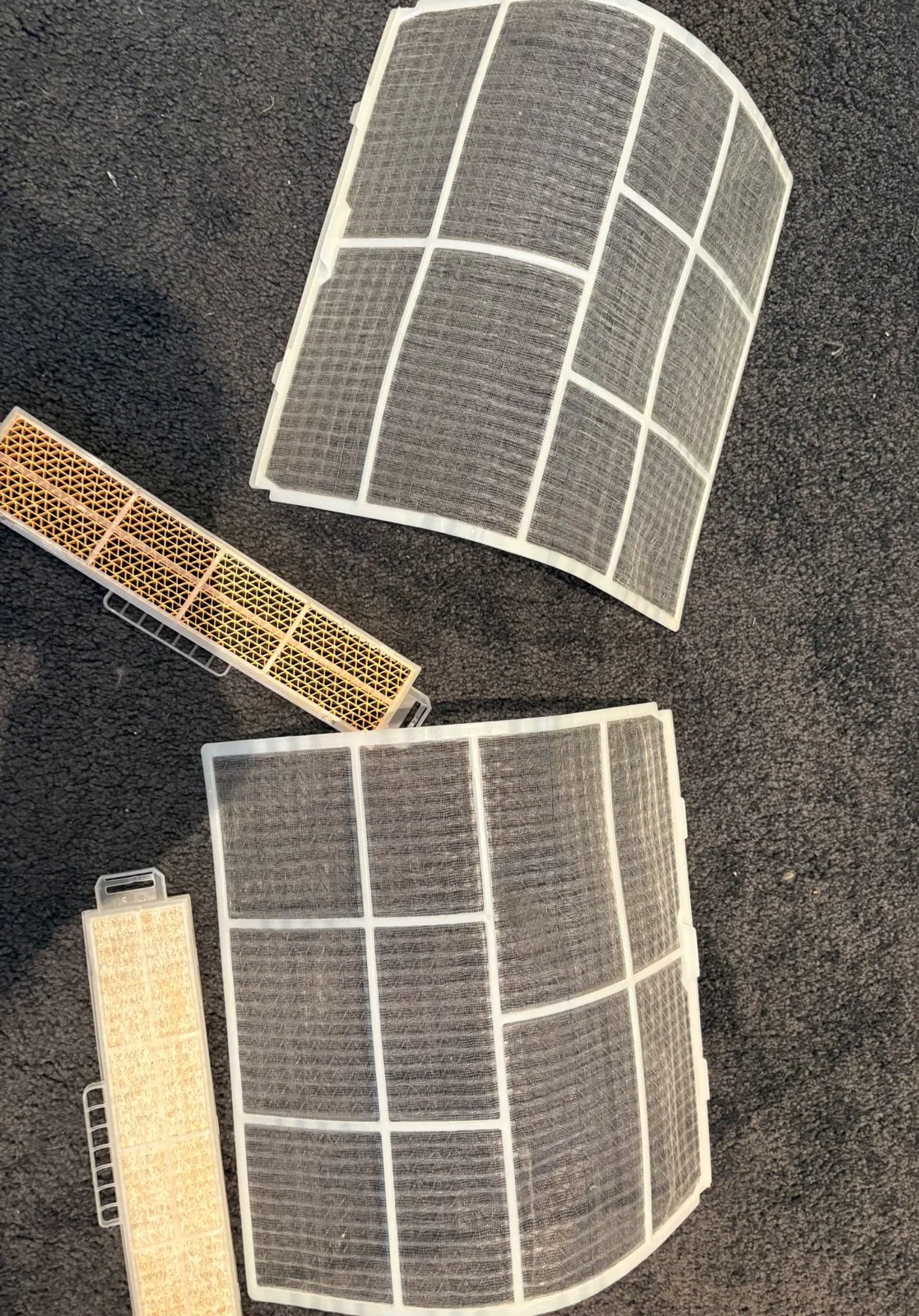 Two cleaned split system mesh filters and two smaller secondary filters laid out on carpet