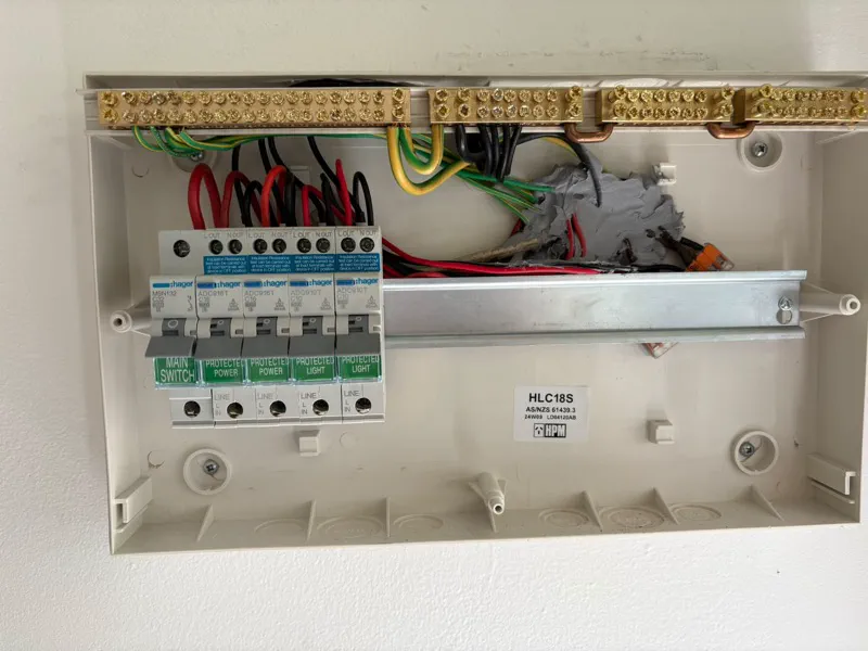 New HPM switchboard with the cover off, showing a Hager main switch and four RCBOs being wired in
