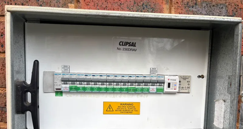 Switchboard in an outdoor meter box with a Hager surge protection device, separate main switches and labelled RCBOs