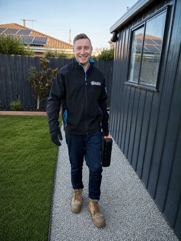 Total Comfort technician in a branded jacket walking along a garden path with a tool case